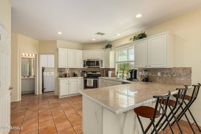 kitchen with visible vents, a peninsula, appliances with stainless steel finishes, white cabinetry, and a kitchen breakfast bar