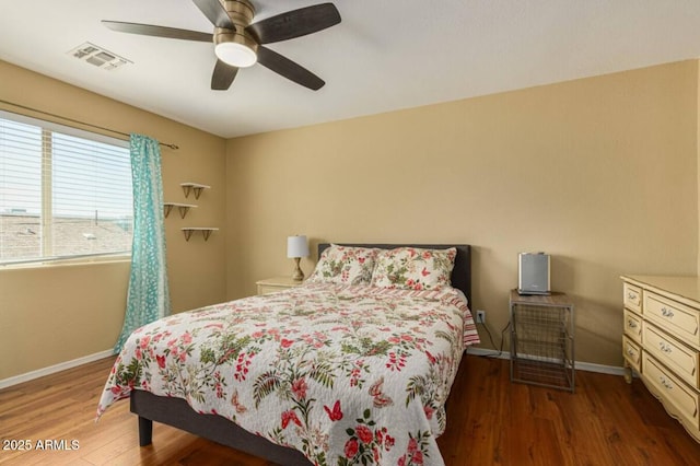 bedroom featuring visible vents, a ceiling fan, baseboards, and wood finished floors