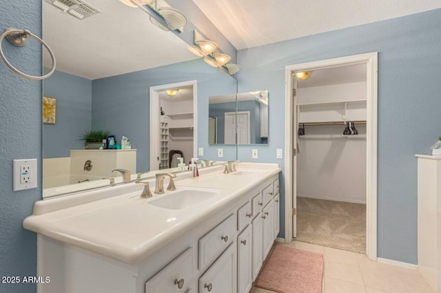 bathroom with a sink, visible vents, double vanity, and tile patterned flooring