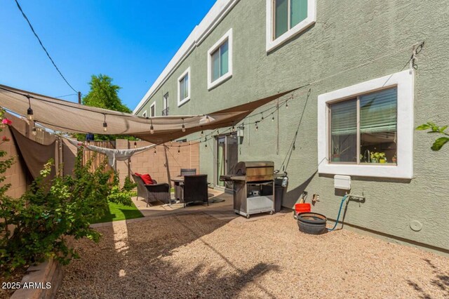 exterior space featuring a patio area, fence, and stucco siding