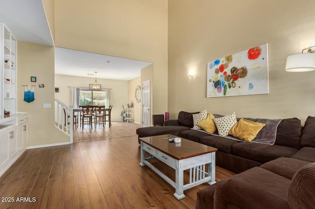 living room with stairway, a towering ceiling, and hardwood / wood-style flooring