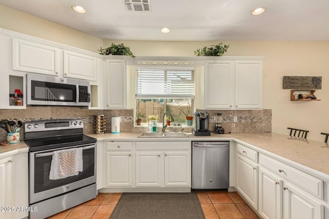 kitchen featuring visible vents, backsplash, light tile patterned floors, appliances with stainless steel finishes, and a sink