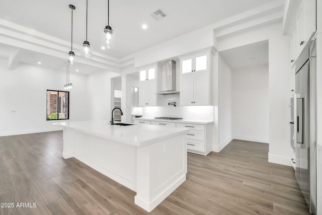 18225 W San Juan Ct, Litchfield Park, AZ 85340 - kitchen featuring wall chimney range hood, a sink, stovetop, a spacious island, and white cabinets