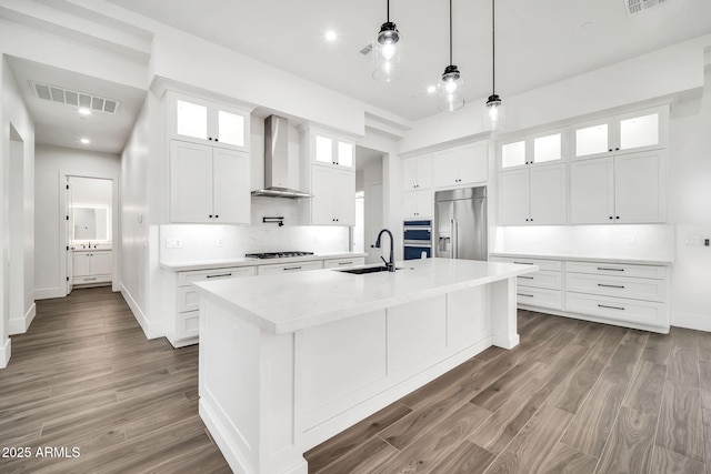 18225 W San Juan Ct, Litchfield Park, AZ 85340 - kitchen featuring wall chimney exhaust hood, stainless steel appliances, a sink, a kitchen island with sink, and tasteful backsplash