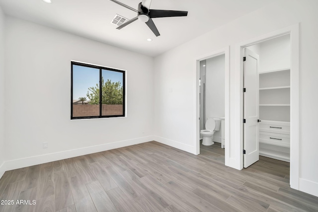 18225 W San Juan Ct, Litchfield Park, AZ 85340 - unfurnished bedroom with light wood-style floors, baseboards, recessed lighting, ensuite bathroom, and a walk in closet