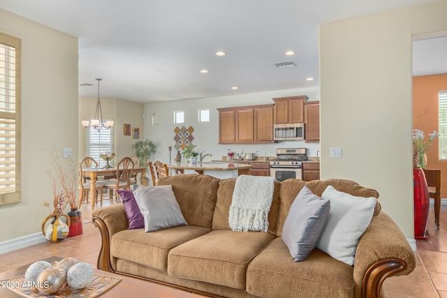 living room featuring a wealth of natural light, light tile patterned floors, and an inviting chandelier