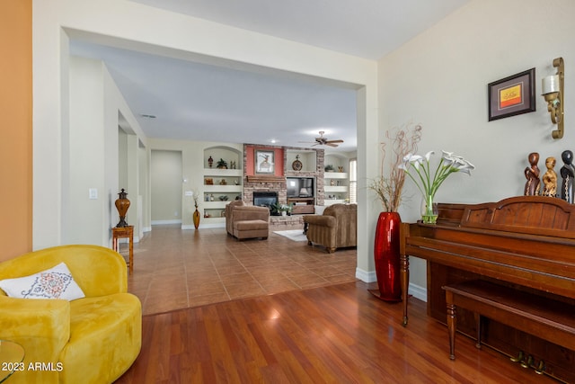 sitting room featuring hardwood / wood-style floors, ceiling fan, a fireplace, and built in shelves