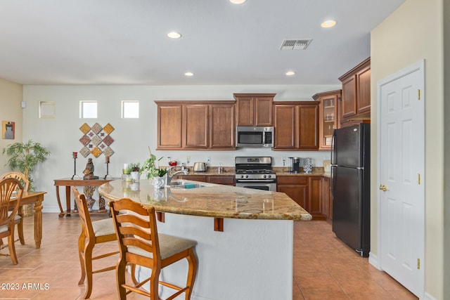 kitchen with light stone countertops, a kitchen breakfast bar, stainless steel appliances, sink, and light tile patterned floors