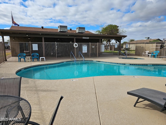 community pool featuring a patio area, cooling unit, and fence