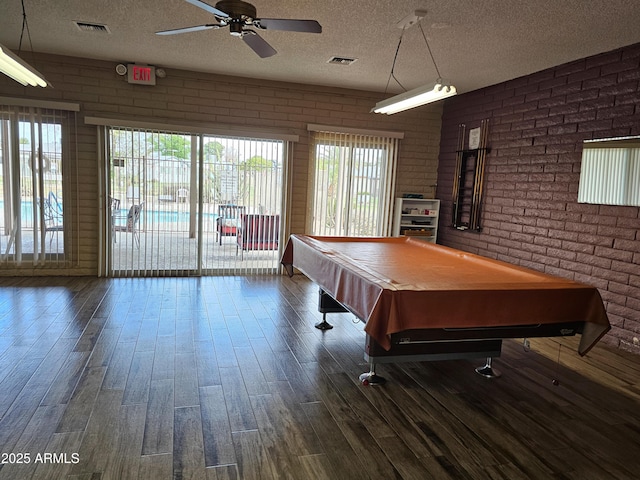 game room with visible vents, brick wall, a textured ceiling, and dark wood-style flooring