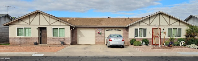 tudor-style house featuring brick siding, stucco siding, driveway, and a garage