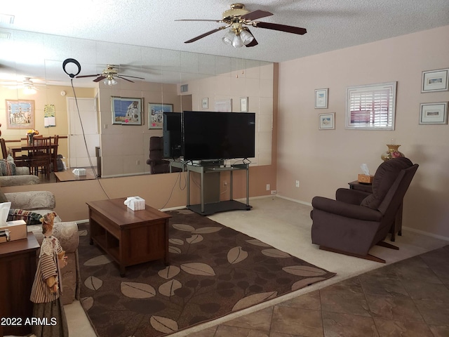 carpeted living room with baseboards, a ceiling fan, visible vents, and a textured ceiling