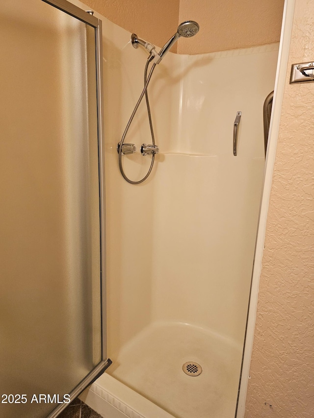 bathroom featuring a shower stall and a textured wall