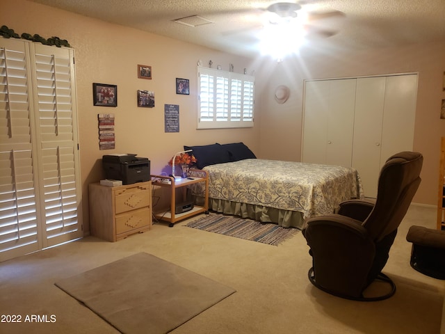 bedroom featuring ceiling fan, carpet, a closet, and a textured ceiling