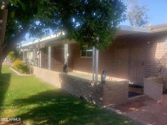 view of side of home with brick siding and a lawn