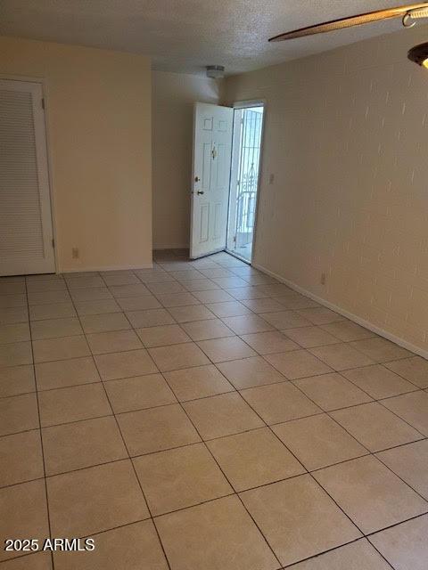 tiled empty room with a textured ceiling