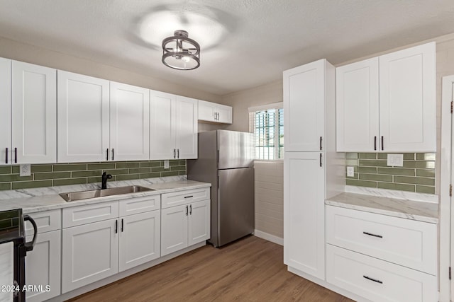 kitchen featuring light hardwood / wood-style floors, stainless steel refrigerator, white cabinetry, and sink