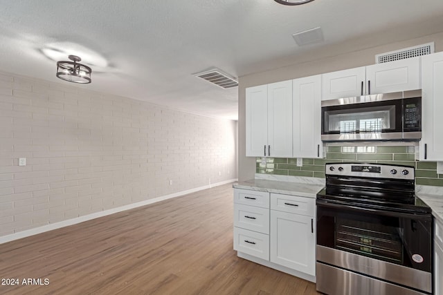 kitchen featuring white cabinets, light wood-type flooring, stainless steel appliances, and light stone countertops