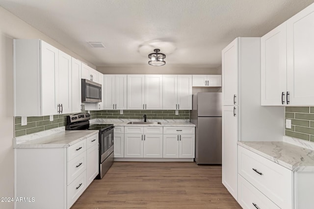 kitchen featuring white cabinets, sink, decorative backsplash, appliances with stainless steel finishes, and wood-type flooring