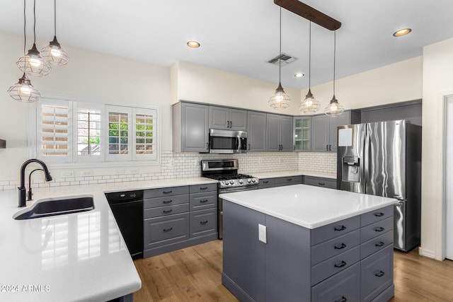 kitchen with stainless steel appliances, a kitchen island, gray cabinets, sink, and light hardwood / wood-style floors