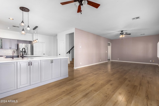 kitchen featuring hardwood / wood-style floors, decorative backsplash, sink, stainless steel fridge with ice dispenser, and decorative light fixtures