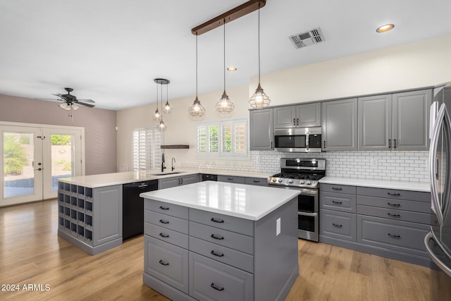 kitchen with gray cabinets, kitchen peninsula, appliances with stainless steel finishes, and a center island