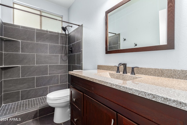 bathroom featuring tile patterned floors, vanity, toilet, and a tile shower