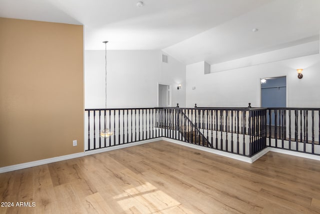 empty room with wood-type flooring and vaulted ceiling