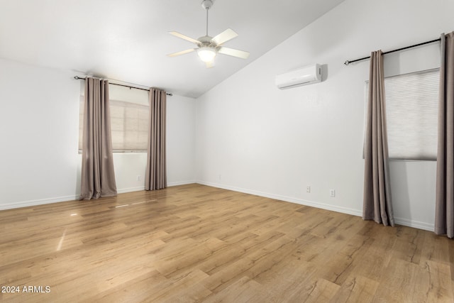 empty room with ceiling fan, light hardwood / wood-style flooring, lofted ceiling, and a wall mounted air conditioner