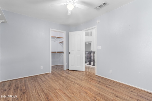 unfurnished bedroom featuring ceiling fan, a closet, light hardwood / wood-style flooring, and a spacious closet