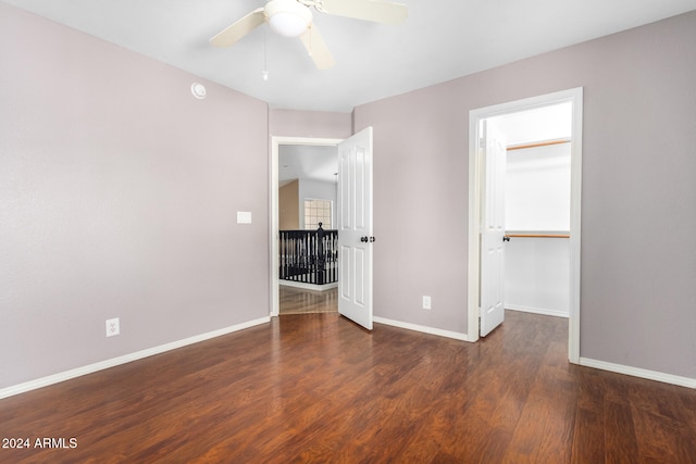 unfurnished bedroom featuring dark wood-type flooring, ceiling fan, a walk in closet, and a closet