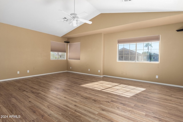 unfurnished room with hardwood / wood-style floors, plenty of natural light, and lofted ceiling