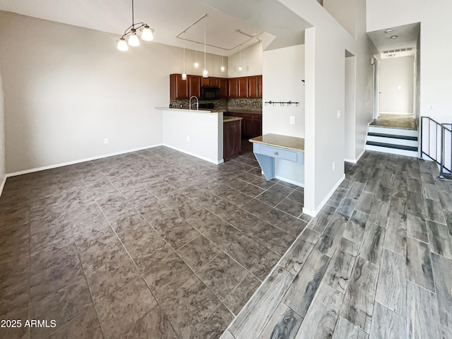kitchen with a peninsula, baseboards, tasteful backsplash, a sink, and black microwave