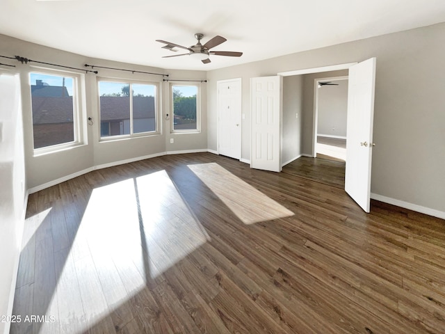 empty room featuring a ceiling fan, dark wood-type flooring, and baseboards
