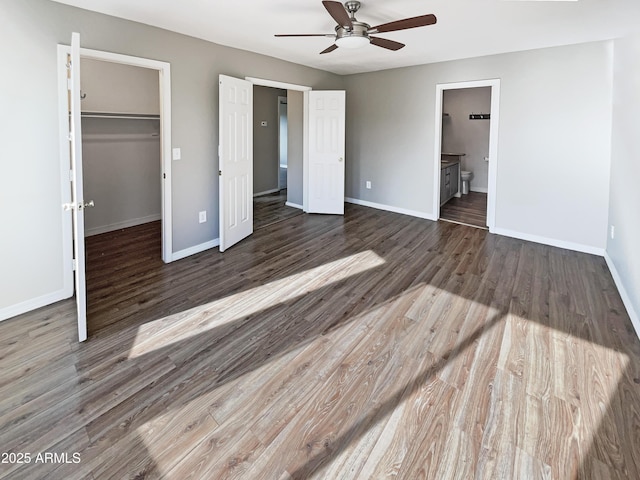 unfurnished bedroom with a spacious closet, baseboards, and wood finished floors