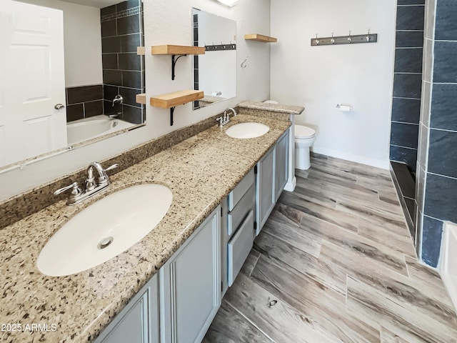 full bath with baseboards, double vanity, a sink, and toilet