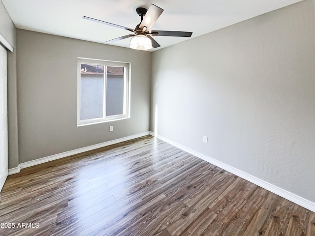 empty room with baseboards, dark wood-style floors, and a ceiling fan