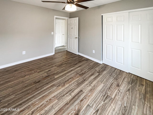 unfurnished bedroom featuring dark wood finished floors, baseboards, a closet, and ceiling fan