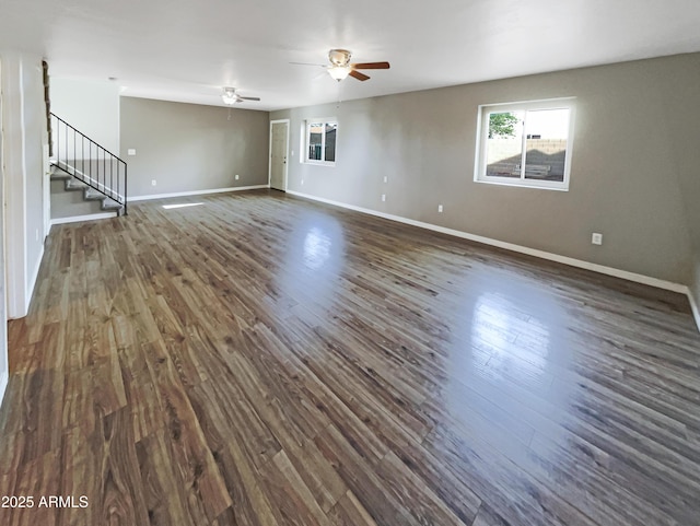 empty room with baseboards, dark wood-style flooring, stairway, and a ceiling fan
