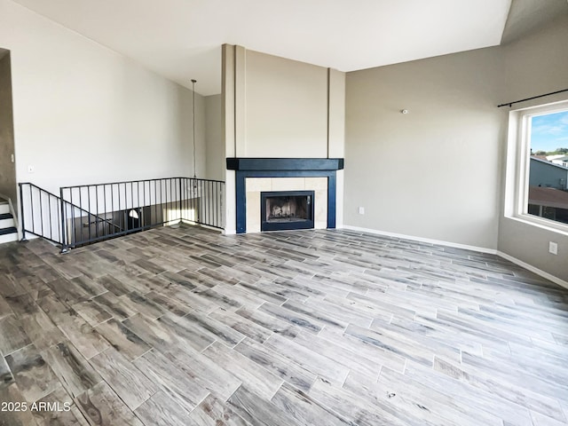 unfurnished living room featuring baseboards, wood finished floors, and a tile fireplace