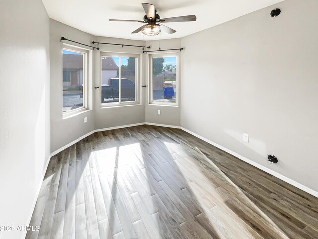 empty room with baseboards, wood finished floors, and ceiling fan