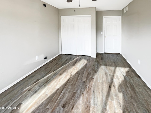 unfurnished bedroom with baseboards, visible vents, a closet, and wood finished floors