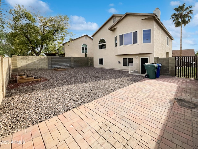 back of property with stucco siding, a gate, a fenced backyard, and a patio