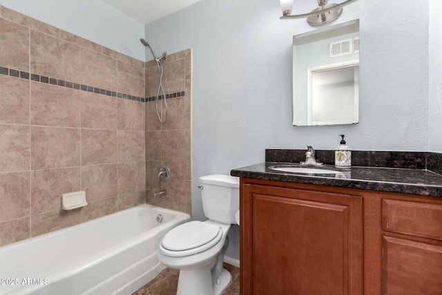 full bathroom with vanity, tiled shower / bath combo, and toilet