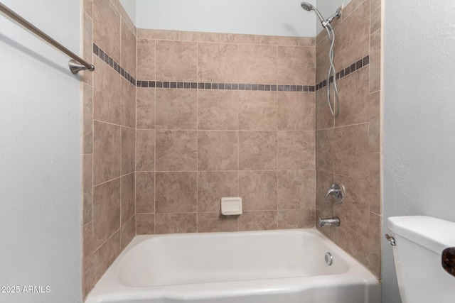 bathroom featuring tiled shower / bath combo and toilet