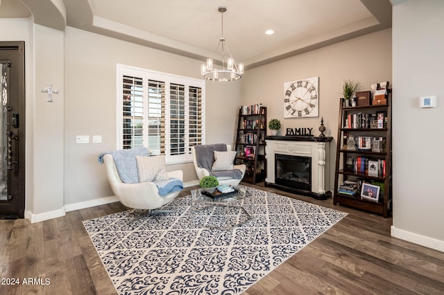 living area with an inviting chandelier, wood-type flooring, and a tray ceiling