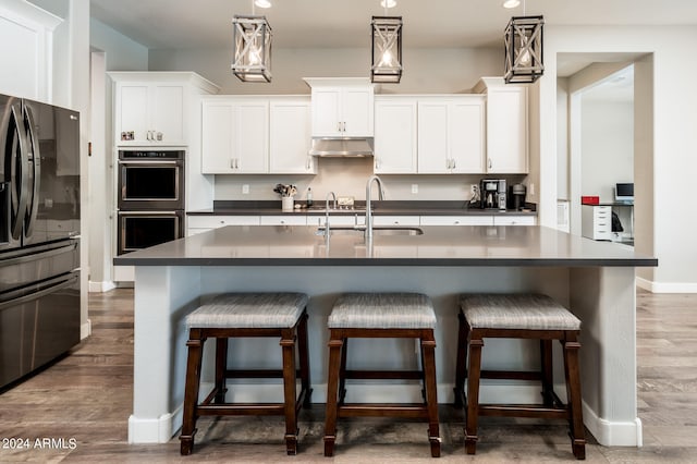 kitchen with pendant lighting, white cabinets, appliances with stainless steel finishes, and dark hardwood / wood-style flooring