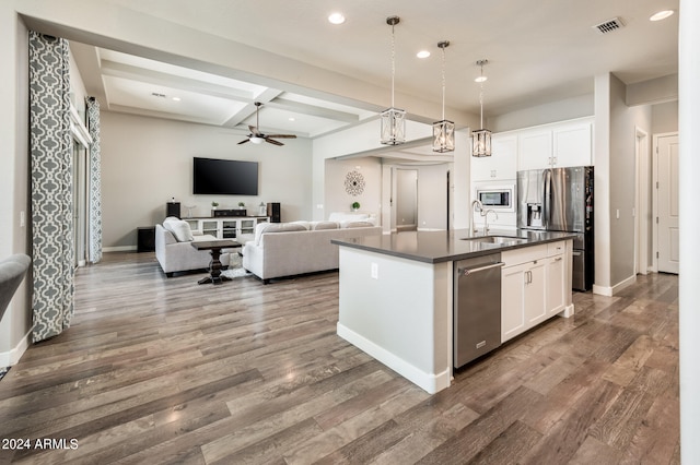 kitchen with appliances with stainless steel finishes, white cabinetry, ceiling fan, decorative light fixtures, and a kitchen island with sink