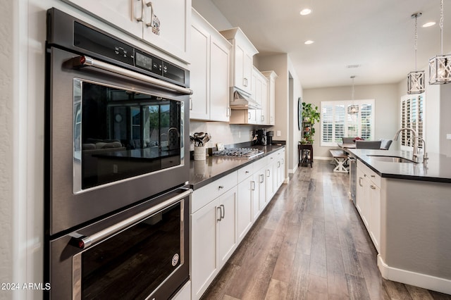 kitchen featuring dark hardwood / wood-style flooring, white cabinetry, decorative light fixtures, and sink