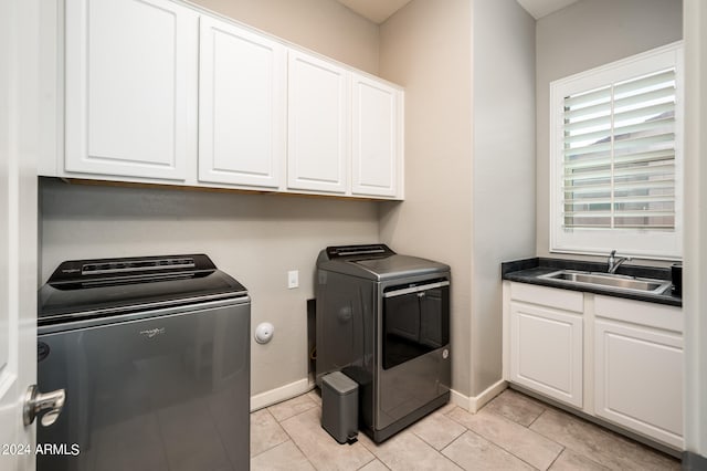 clothes washing area with cabinets, independent washer and dryer, light tile patterned floors, and sink